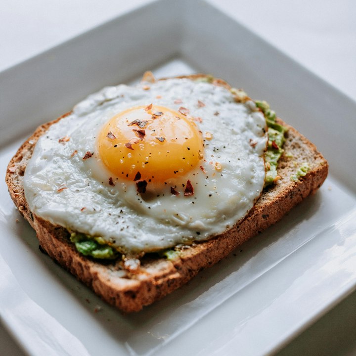 Avocado toast topped with a fried egg and chili flakes